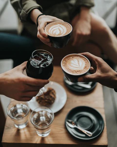 Friends sharing lattes and pastries at a table