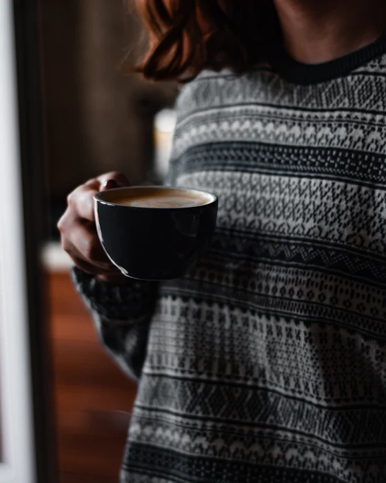 Person in a knit sweater holding a coffee mug