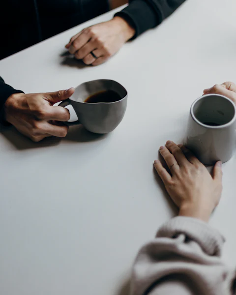 Two people with coffee cups at a white table